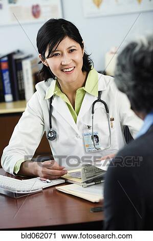 Stock Image - Kazakh female doctor listening to patient. Fotosearch