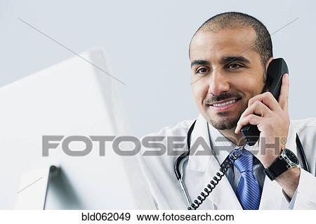 Stock Photo - Lebanese male doctor talking on telephone. Fotosearch