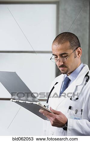Stock Image - Lebanese male doctor writing in medical chart. Fotosearch