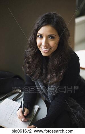 Stock Image - Middle Eastern woman writing in notebook. Fotosearch