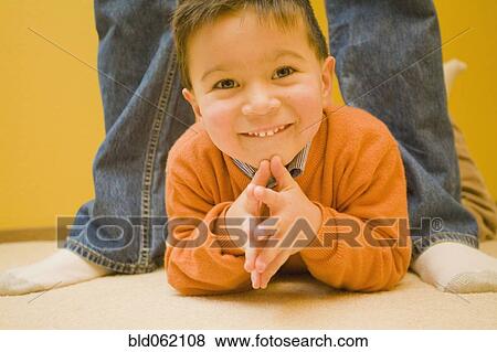 Stock Photo - Mixed race boy laying on floor. Fotosearch