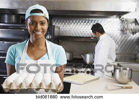 Mixed Race female kitchen worker holding eggs View Large Photo Image Stock Image - Mixed Race female kitchen worker holding eggs. Fotosearch