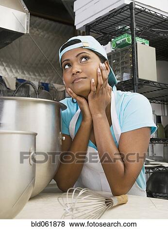 Stock Photo - Mixed Race female kitchen worker thinking. Fotosearch