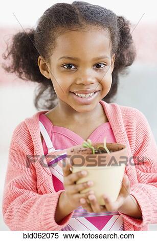 Mixed race girl holding seedling in pot View Large Photo Image Stock Photography - Mixed race girl holding seedling in pot. Fotosearch