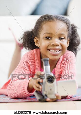 Stock Photograph - Mixed race girl holding video camera. Fotosearch