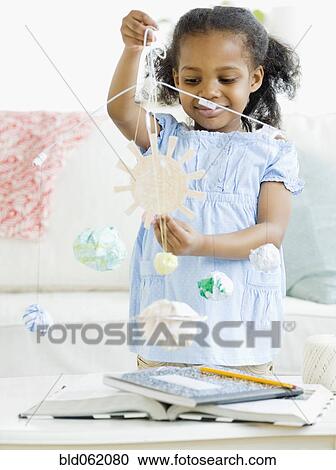 Mixed race girl making solar system mobile View Large Photo Image Stock Image - Mixed race girl making solar system mobile. Fotosearch
