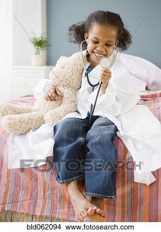 Mixed race girl playing doctor with teddy bear View Large Photo Image Picture - Mixed race girl playing doctor with teddy bear. Fotosearch