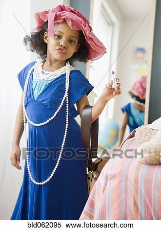 Stock Photography - Mixed race girl playing dress-up in mother’s clothes. Fotosearch