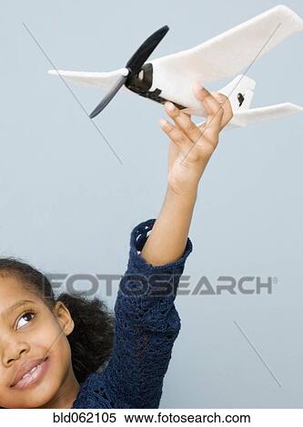 Stock Photography - Mixed race girl playing with toy airplane. Fotosearch