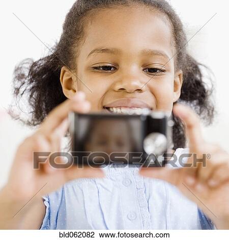 Stock Image - Mixed race girl taking self-portrait with digital camera. Fotosearch