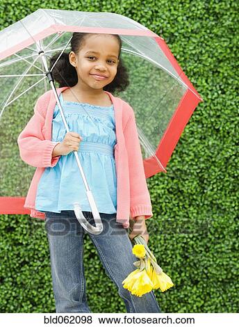 Stock Photo - Mixed race girl with umbrella and flowers. Fotosearch