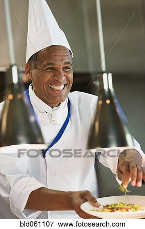 Mixed Race male chef garnishing plate of food View Large Photo Image Stock Photo - Mixed Race male chef garnishing plate of food. Fotosearch
