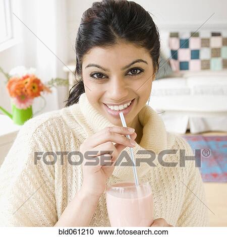Stock Image - Mixed Race woman drinking milkshake. Fotosearch