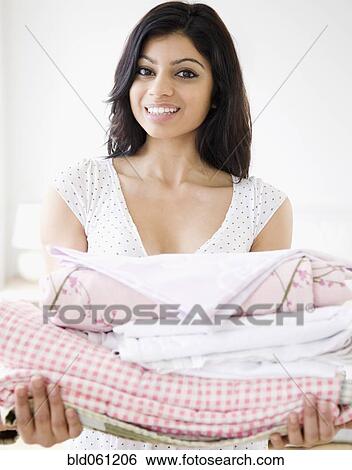 Mixed Race woman holding folded laundry View Large Photo Image Stock Photograph - Mixed Race woman holding folded laundry. Fotosearch