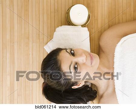 Picture - Mixed Race woman laying next to lit candle. Fotosearch