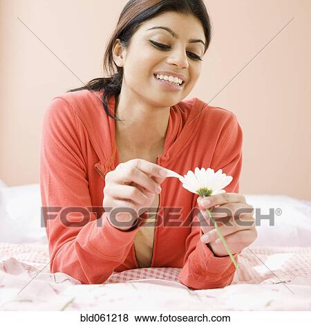 Stock Photo - Mixed Race woman pulling petals off flower. Fotosearch