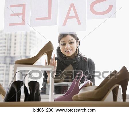 Stock Image - Mixed Race woman shoe shopping. Fotosearch