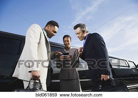 Stock Photo - Multi-ethnic businesspeople looking at cell phone. Fotosearch