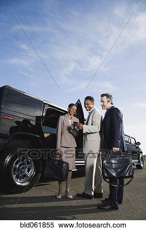 Stock Photography - Multi-ethnic businesspeople next to limousine. Fotosearch