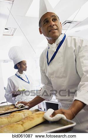 Stock Photo - Multi-ethnic chefs carrying food in kitchen. Fotosearch