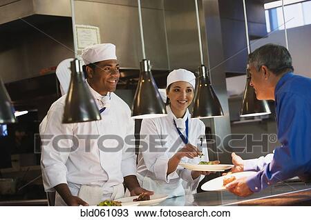 Multi-ethnic chefs handing out plates of food View Large Photo Image Stock Image - Multi-ethnic chefs handing out plates of food. Fotosearch