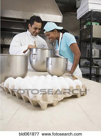 Multi-ethnic chefs looking at batter View Large Photo Image Stock Photo - Multi-ethnic chefs looking at batter. Fotosearch