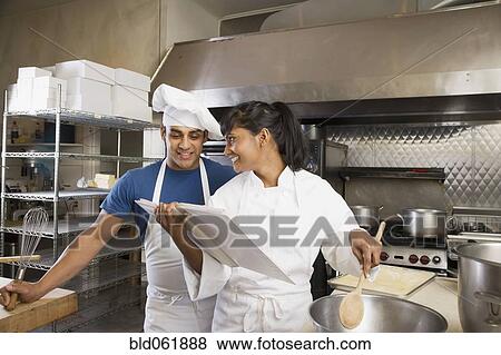 Stock Photo - Multi-ethnic chefs looking at cookbook. Fotosearch