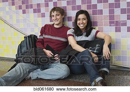 Multi-ethnic couple sitting against wall View Large Photo Image Stock Image - Multi-ethnic couple sitting against wall. Fotosearch