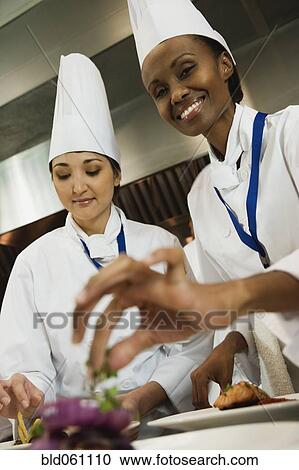 Multi-ethnic female chefs garnishing plates of food View Large Photo Image Stock Image - Multi-ethnic female chefs garnishing plates of food. Fotosearch