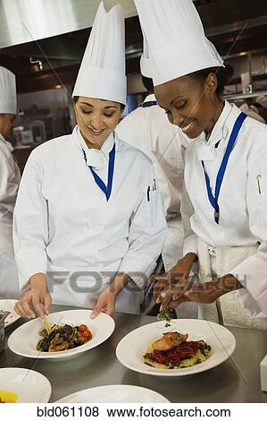 Multi-ethnic female chefs garnishing plates of food View Large Photo Image Stock Photo - Multi-ethnic female chefs garnishing plates of food. Fotosearch