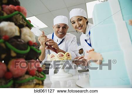 Stock Photo - Multi-ethnic pastry chefs decorating cake. Fotosearch