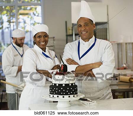 Stock Photography - Multi-ethnic pastry chefs next to cake. Fotosearch