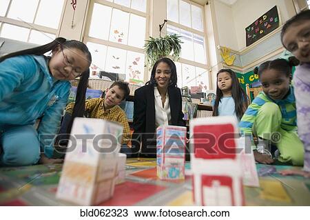 Stock Image - Multi-ethnic students in classroom with teacher. Fotosearch