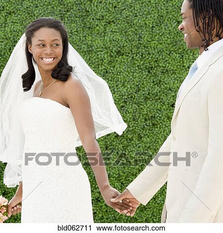African bride and groom holding hands walking View Large Photo Image Stock Image - African bride and groom holding hands walking. Fotosearch