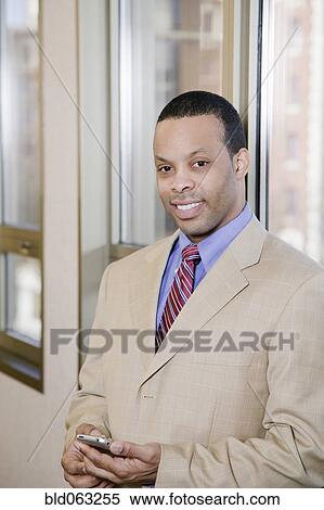 Stock Photography - African businessman holding cell phone. Fotosearch