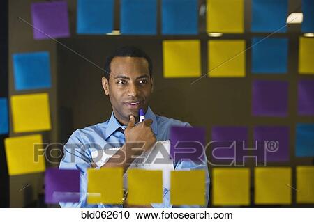 Stock Image - African businessman reviewing sticky notes. Fotosearch