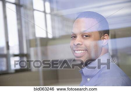 Stock Photograph - African businessman smiling through window. Fotosearch