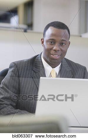 African businessman working on laptop View Large Photo Image Stock Photo - African businessman working on laptop. Fotosearch