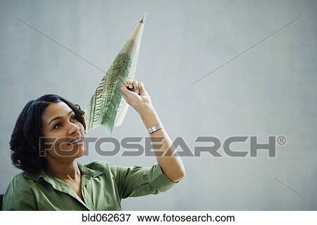 Stock Photo - African businesswoman holding money paper airplane. Fotosearch
