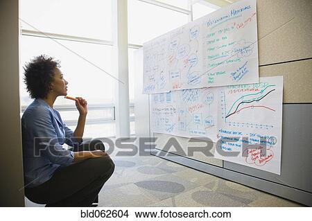 Picture - African businesswoman reviewing notes in office. Fotosearch