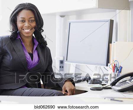 Stock Image - African businesswoman smiling in office. Fotosearch