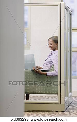 Stock Image - African businesswoman working on laptop in office. Fotosearch