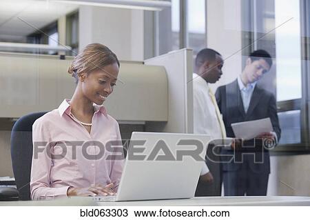 Stock Image - African businesswoman working on laptop in office. Fotosearch