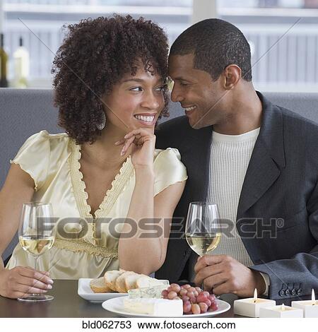 Stock Image - African couple dining at restaurant. Fotosearch