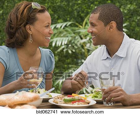 Stock Image - African couple eating on patio. Fotosearch