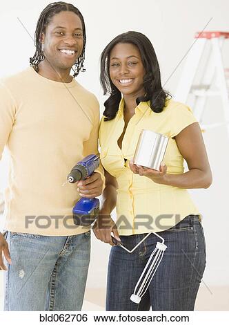 Stock Photograph - African couple holding home improvement tools. Fotosearch