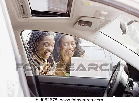 Stock Photography - African couple looking at car for sale. Fotosearch