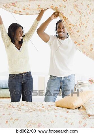 Stock Image - African couple making bed. Fotosearch