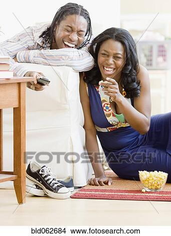 Picture - African couple watching television in living room. Fotosearch