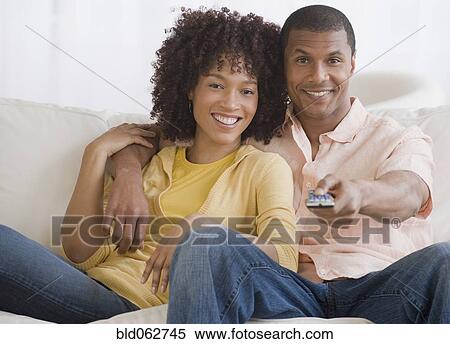 Stock Photography - African couple watching television. Fotosearch